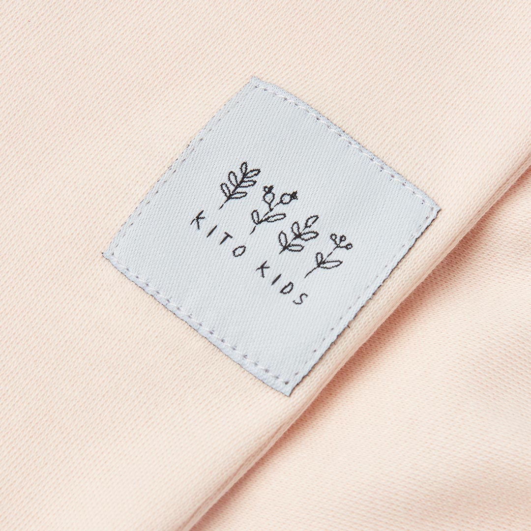 Bavoir pour bébé rose poudré avec un liseré et des cordons blancs à nouer.