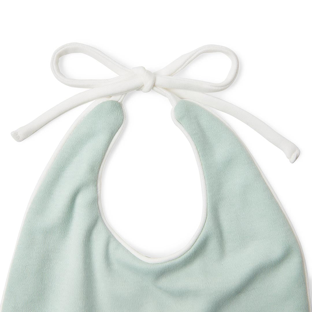 Bavoir souple vert clair pour bébé avec de longs cordons à nouer blancs.