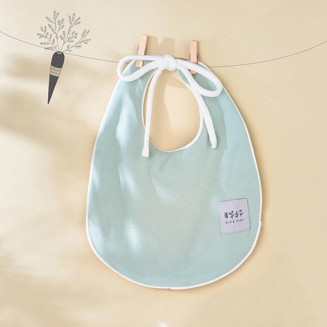 Bavoir de naissance vert menthe clair de la marque Kito Kids avec des attaches blanches croisées.