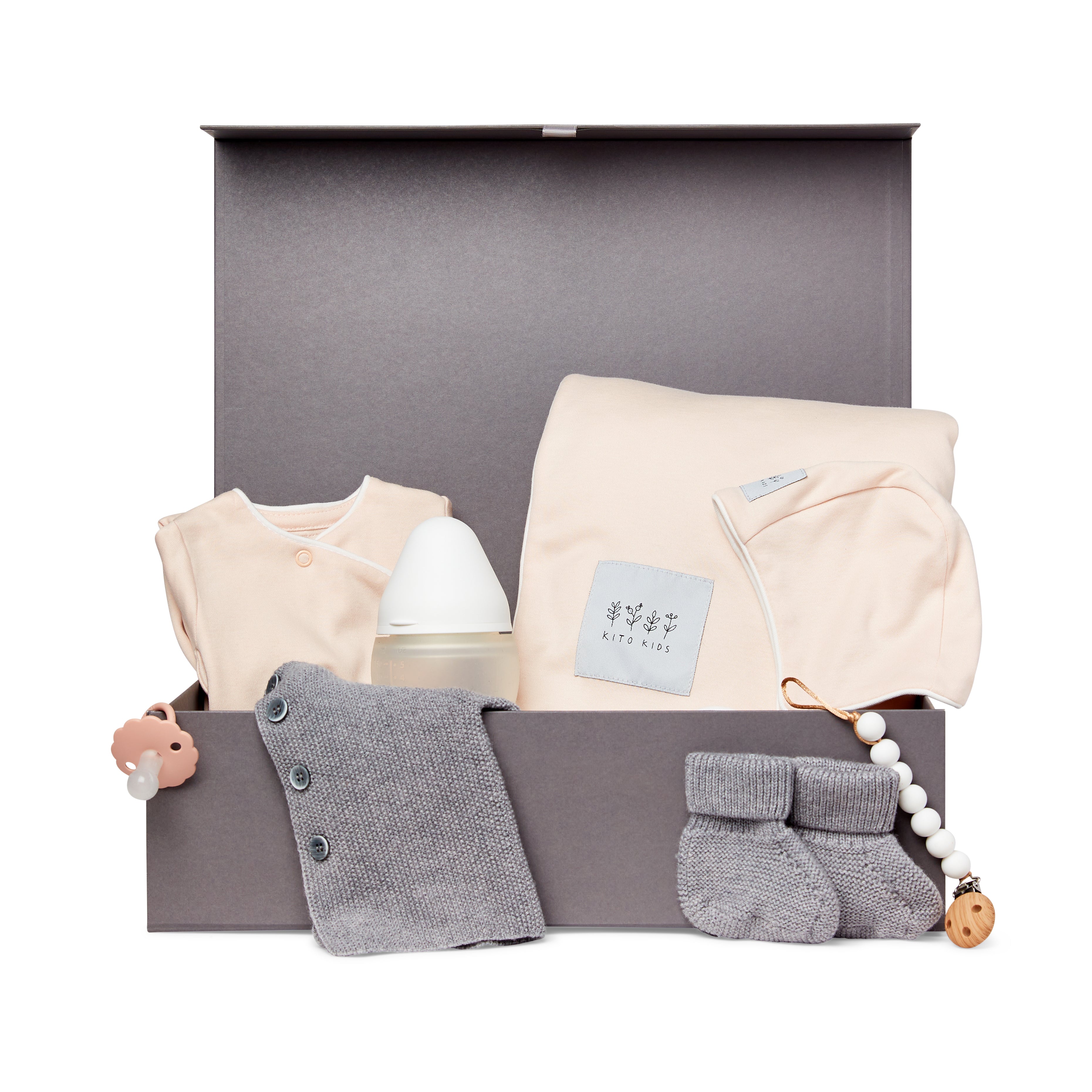 Coffret naissance Kito Kids avec couverture rose poudré, cardigan en laine mérinos gris, brassière rose poudré, chaussons, biberon, tétine et attache-tétine.