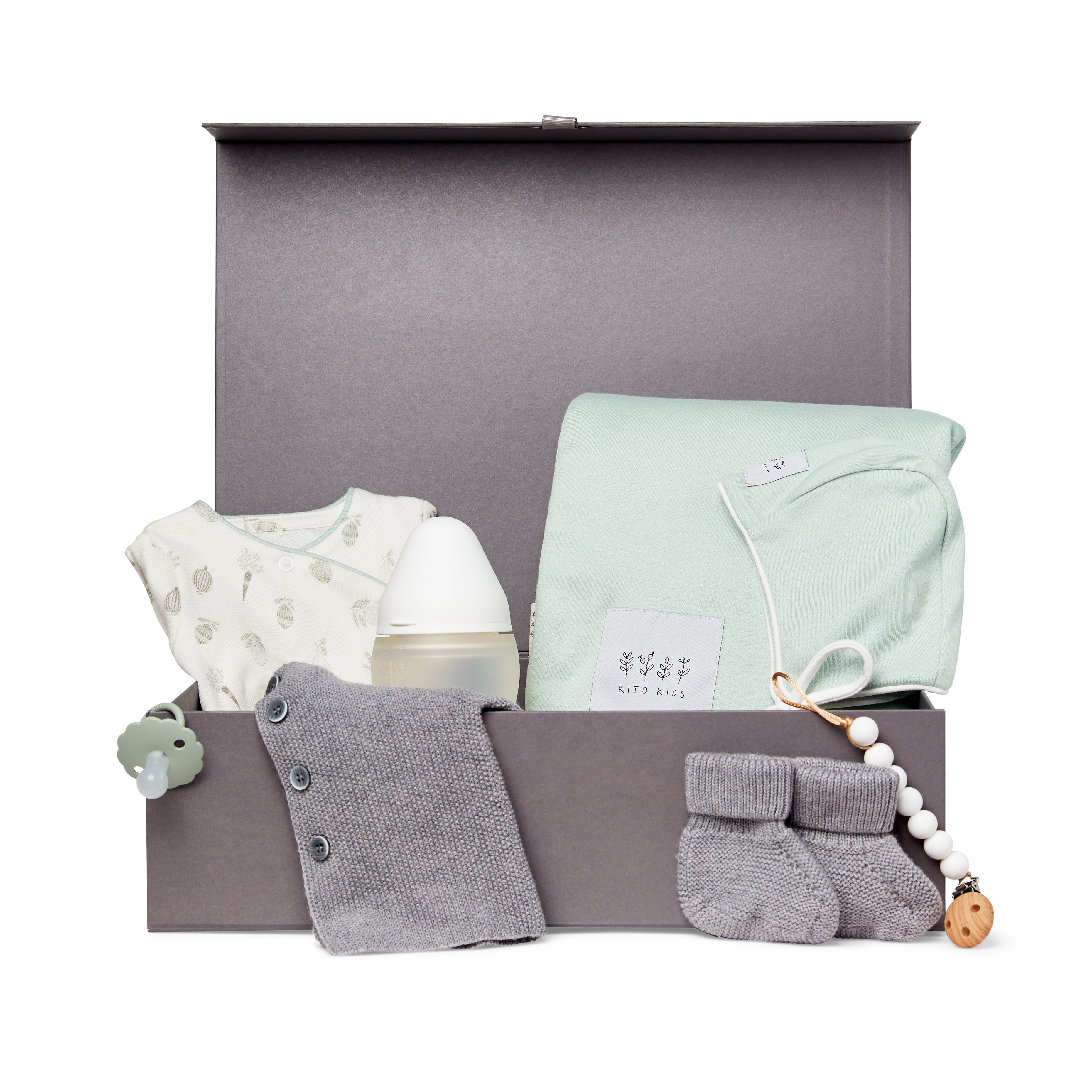 Coffret cadeau de naissance Kito Kids avec couverture vert sauge, cardigan en laine mérinos, chaussons, biberon, attache-tétine et vêtements pour bébé.