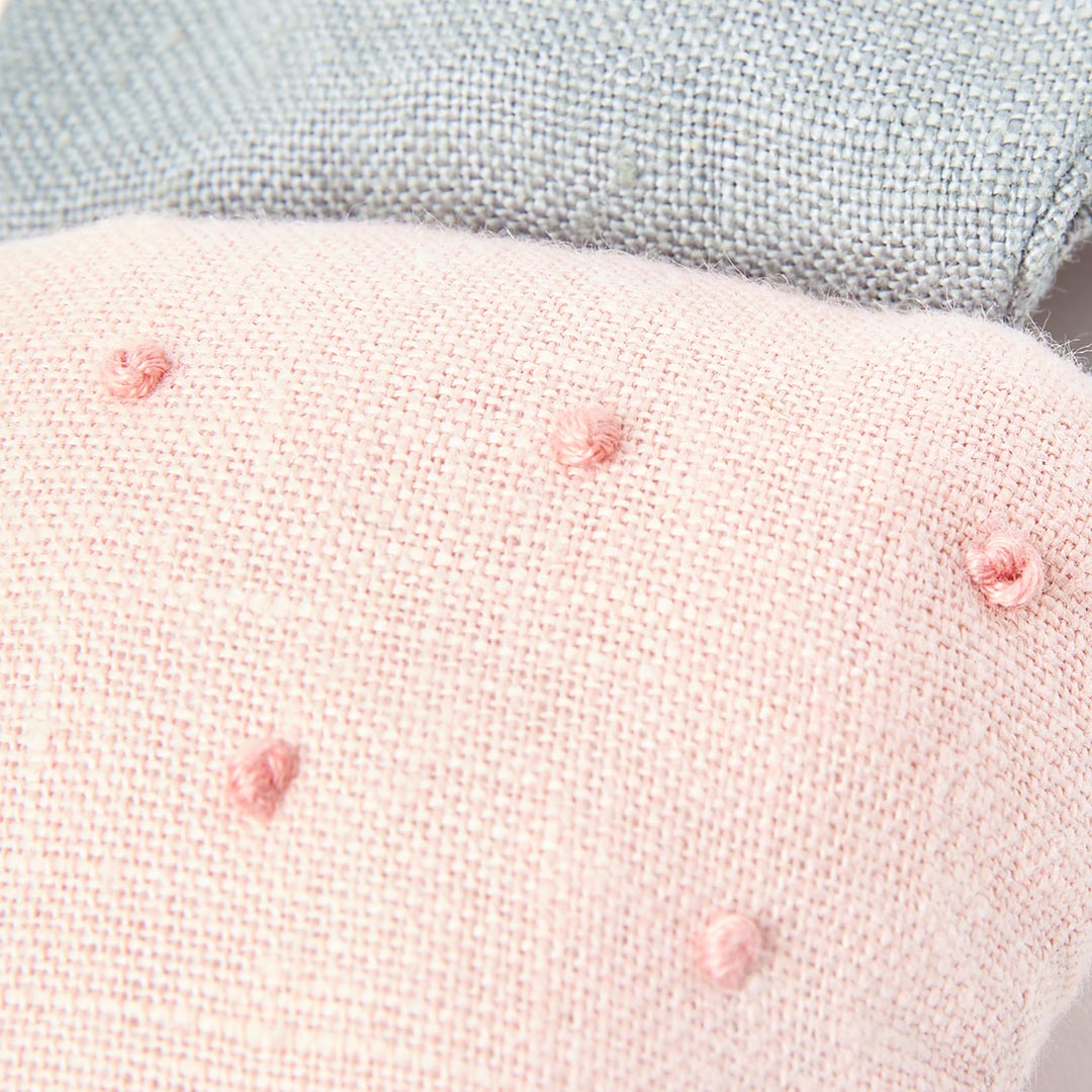 Détail des broderies et de la matière saine du hochet d'éveil fraise pour bébés.