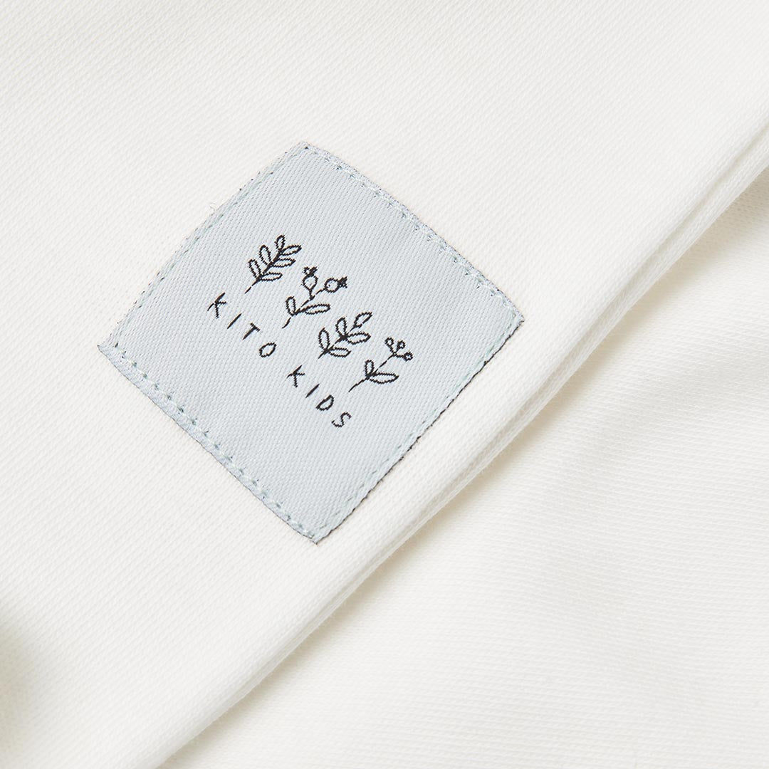 Bavoir pour bébé blanc écru avec des cordons à nouer.