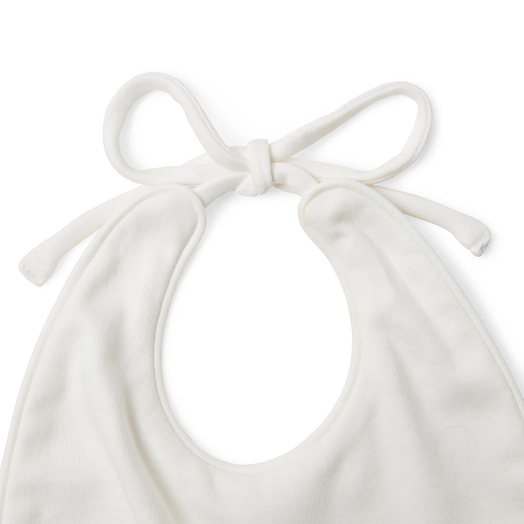 Bavoir souple blanc cassé pour bébé avec de longs cordons à nouer blancs, présenté à plat sur fond blanc.