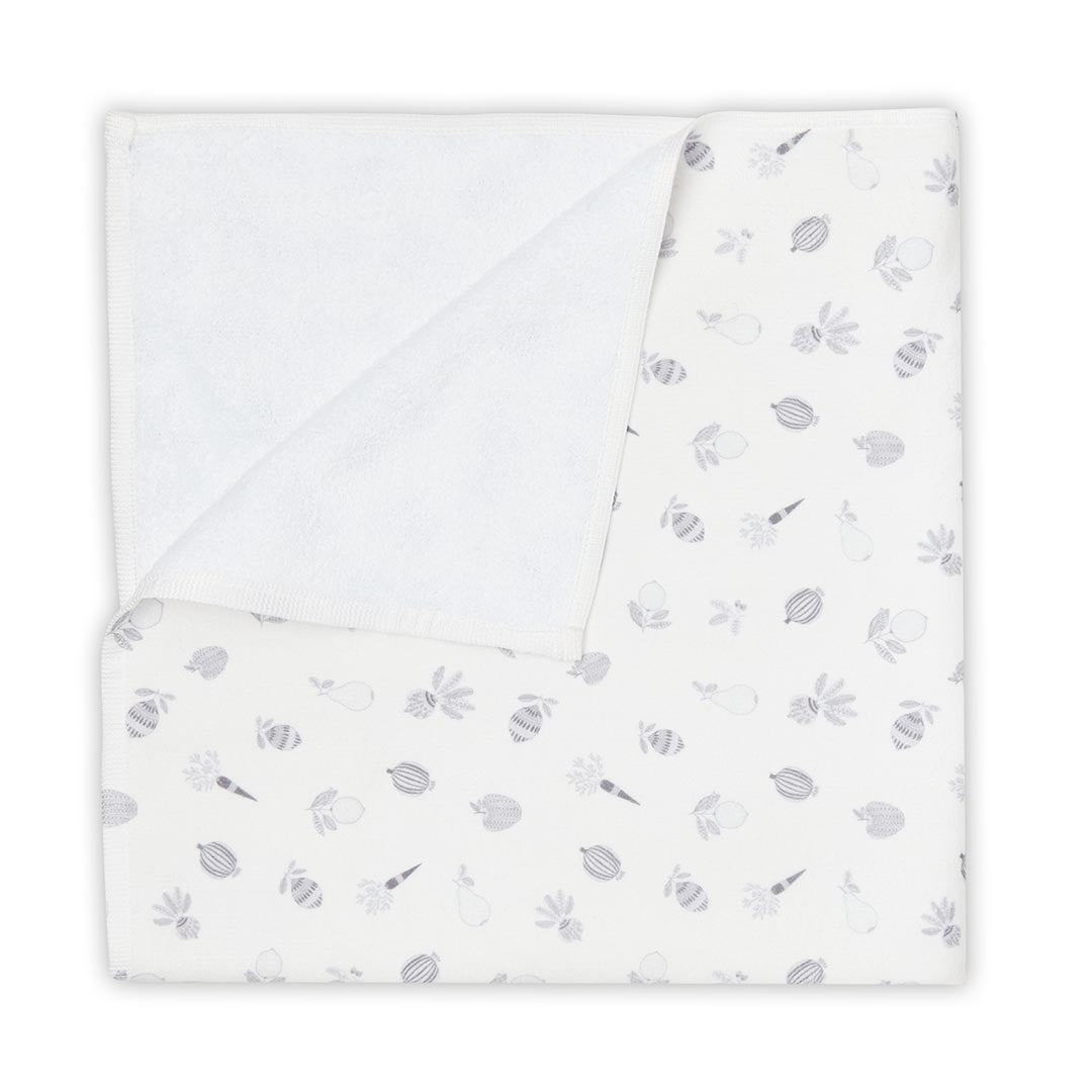 Gros plan sur les finitions d'une serviette de bain blanche pour bébé, montrant l'ourlet tressé et un motif imprimé de citron stylisé.