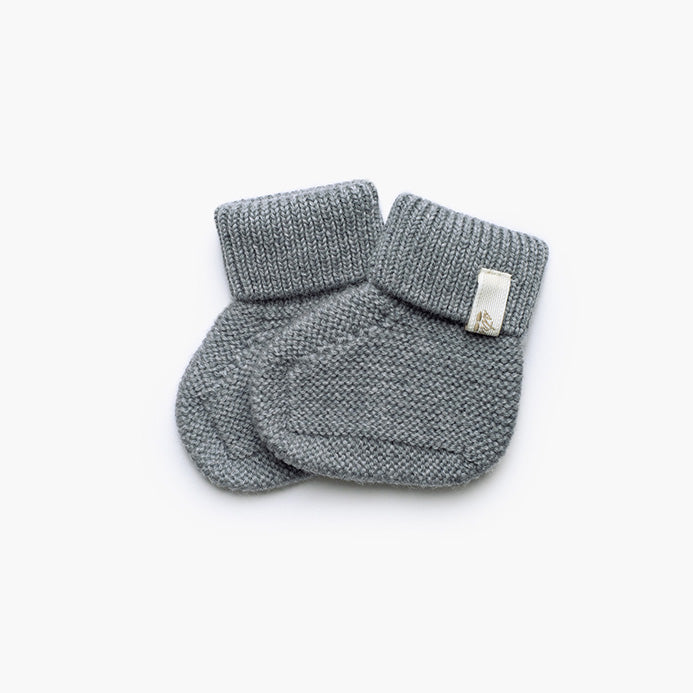 Paire de petits chaussons pour bébé tricotés en laine grise souple et chaude, parfaits pour garder les pieds des nouveau-nés bien au chaud.