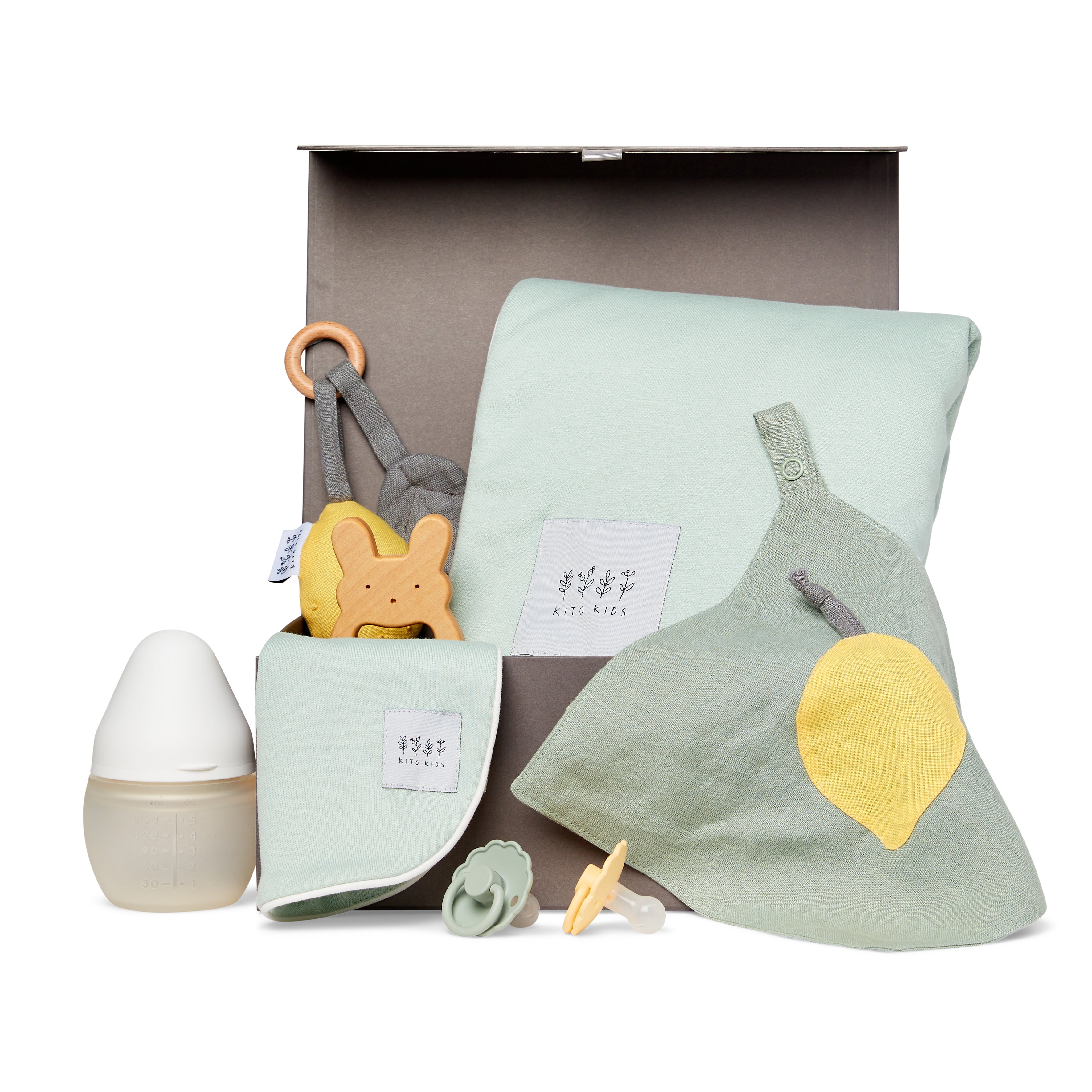 Coffret cadeau de naissance écoresponsable Kito Kids comprenant un lange en coton bio, un bavoir, un hochet en bois, des tétines et un biberon pour les besoins essentiels de bébé.