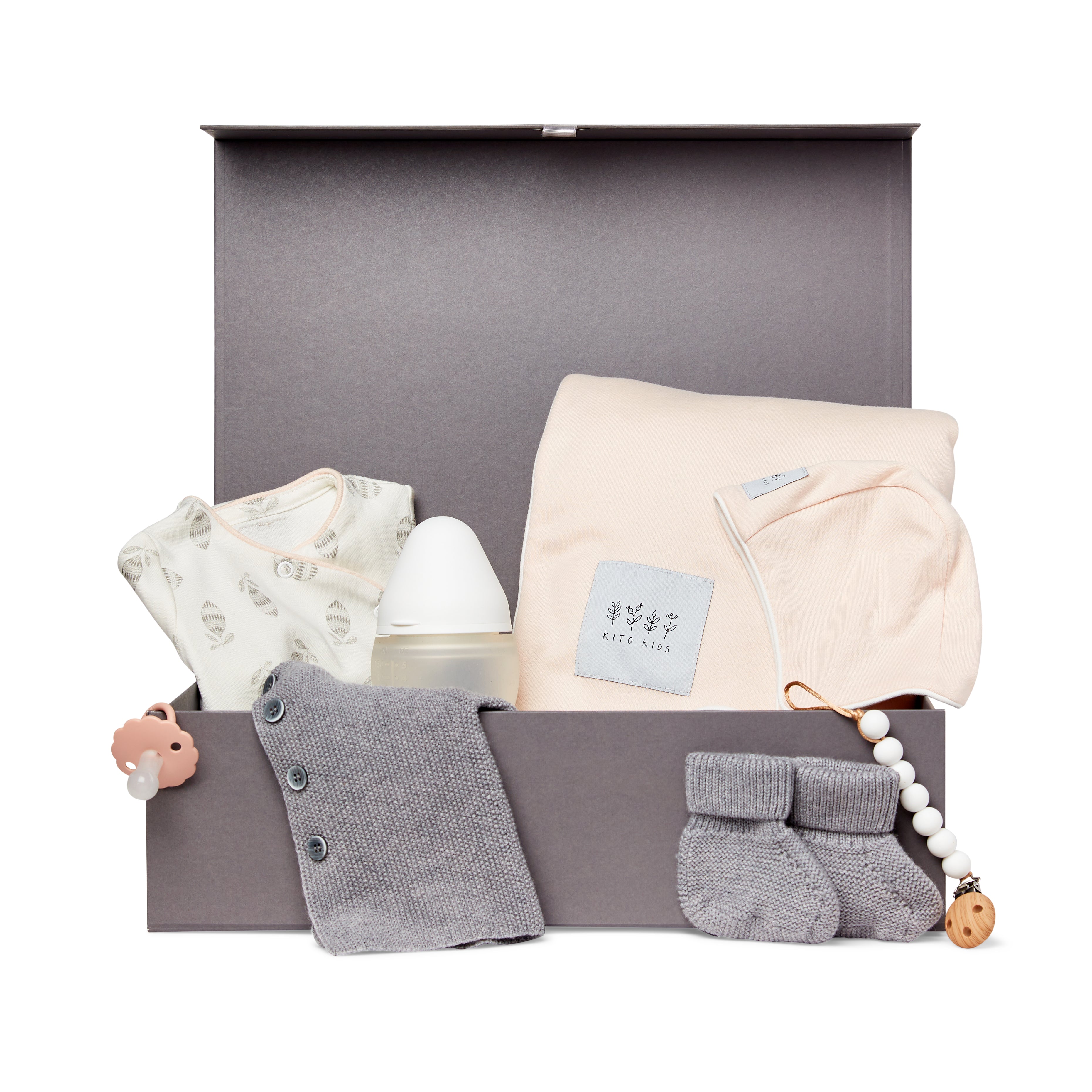 Coffret cadeau naissance Kito Kids avec couverture rose poudré, cardigan en laine mérinos gris, chaussons, biberon, body imprimé et attache-tétine.