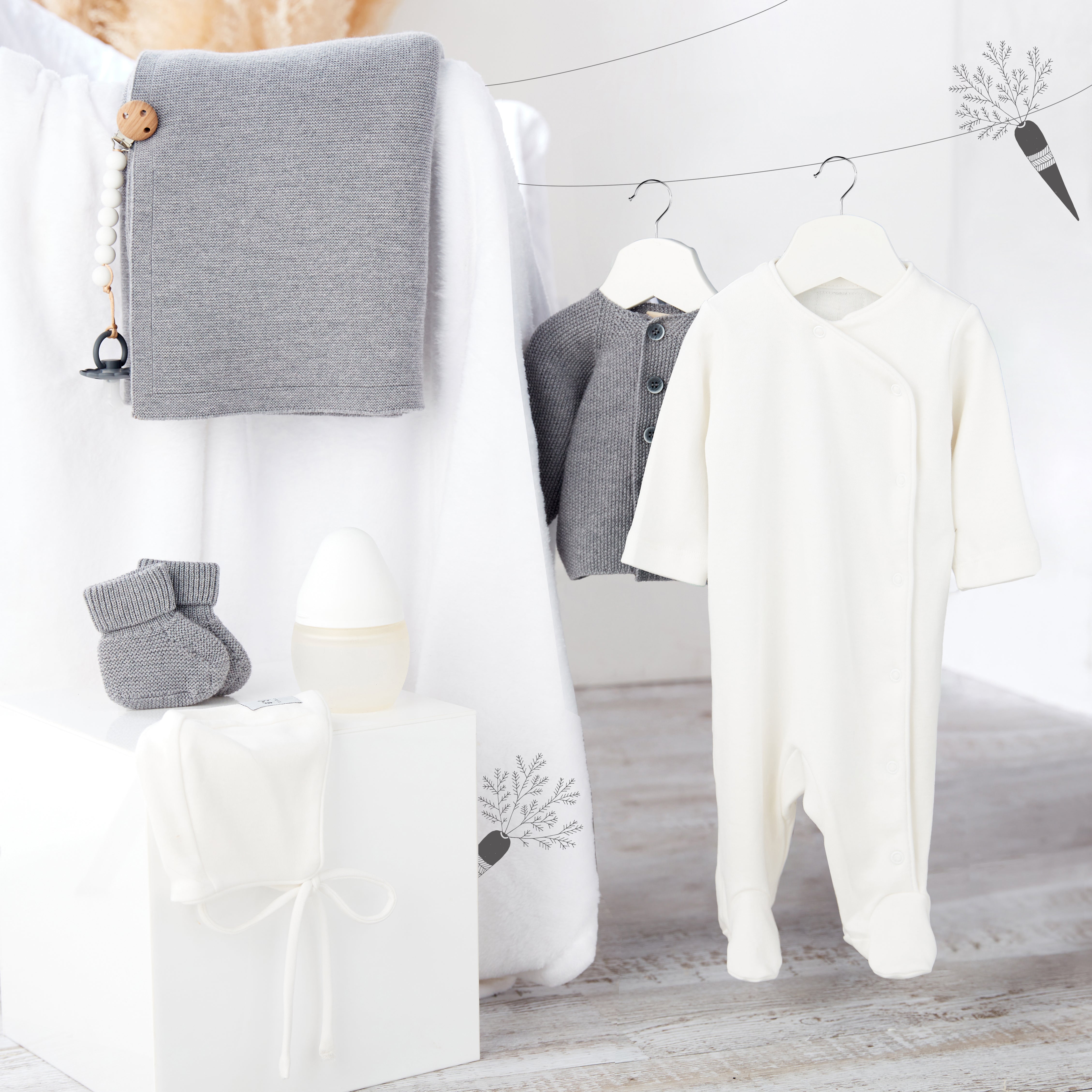Collection naissance Kito Kids avec couverture grise, pyjama blanc, cardigan en laine mérinos gris, chaussons, biberon et attache-tétine.
