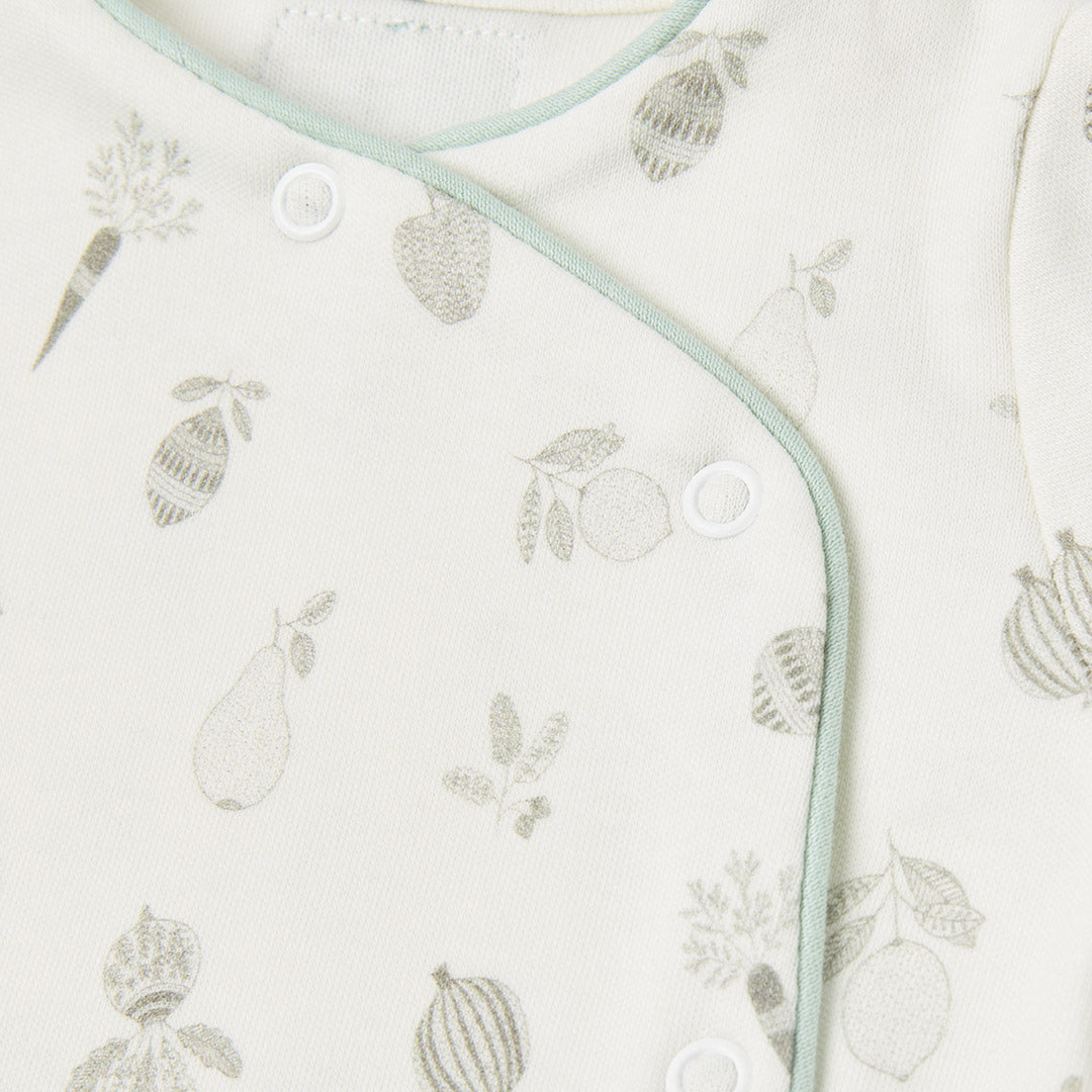 Boutons-pression sans nickel sur l'encolure croisée d'un pyjama en coton biologique pour bébé, conçus pour un habillage sécurisé, rapide et respectueux de la peau sensible des nouveau-nés.