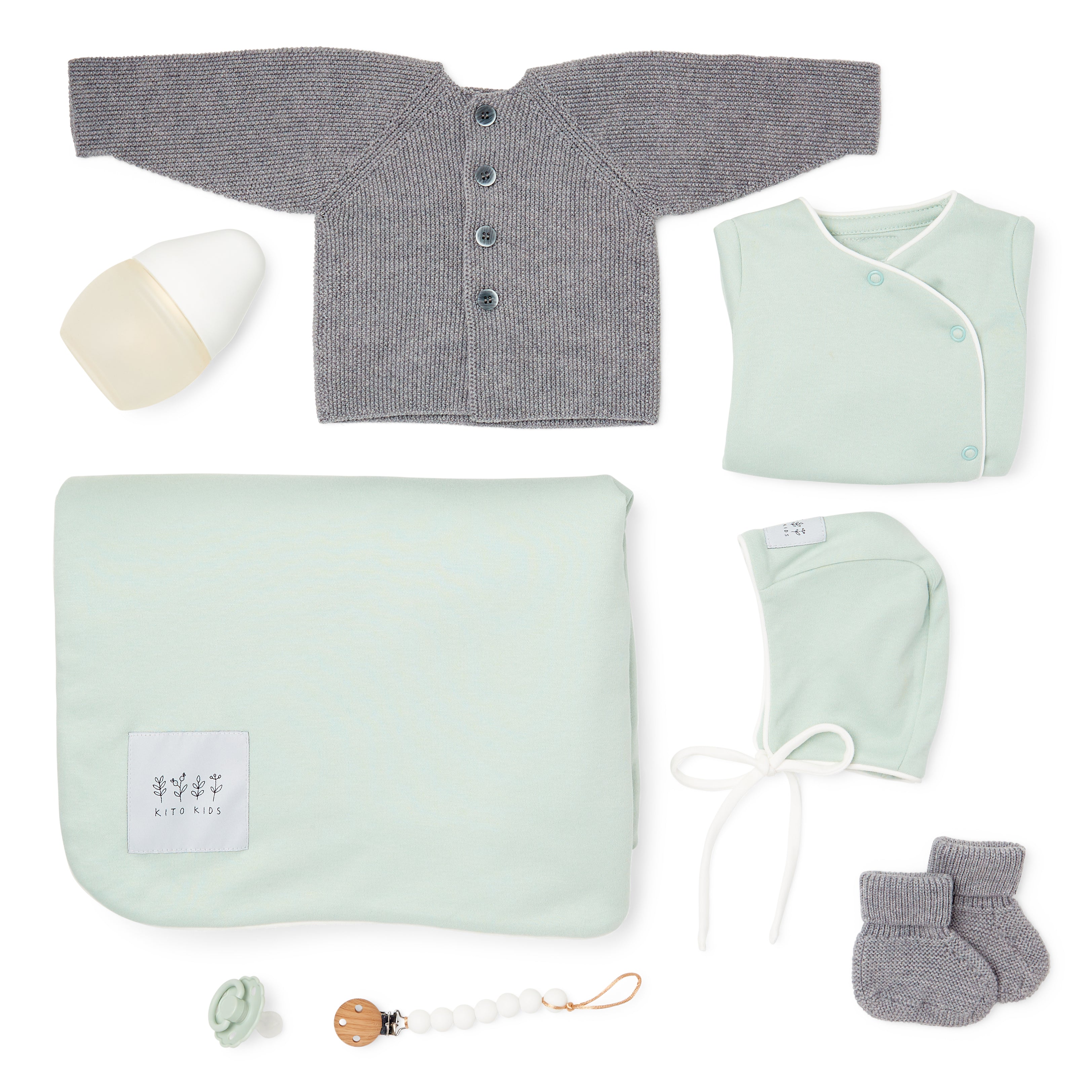 Ensemble naissance Kito Kids avec couverture vert d’eau, cardigan en laine mérinos gris, brassière vert d’eau, bonnet, chaussons, biberon, tétine et attache-tétine.