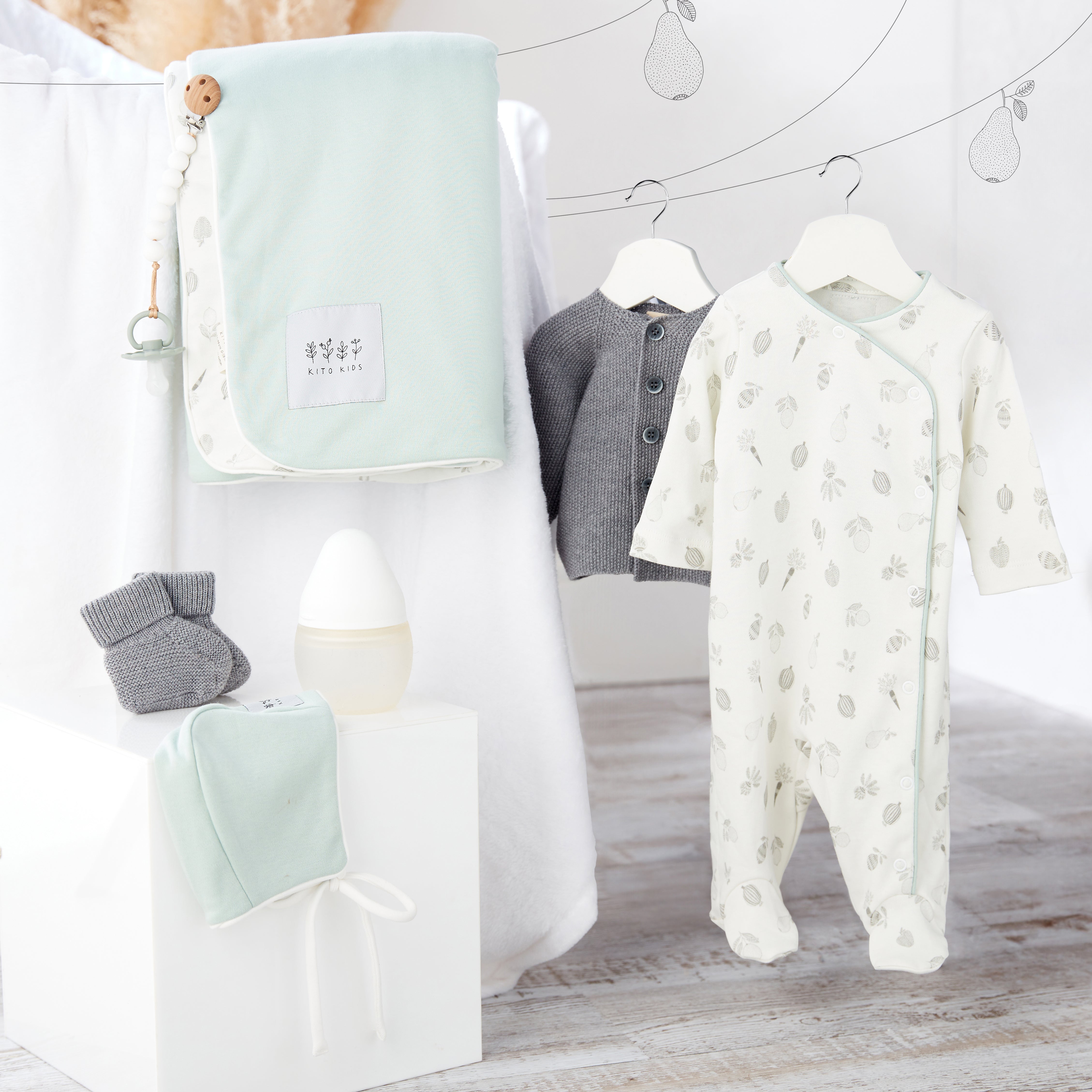 Ensemble de naissance pour bébé en vert sauge et laine mérinos comprenant couverture, pyjama, cardigan, bonnet, chaussons et accessoires Kito Kids.