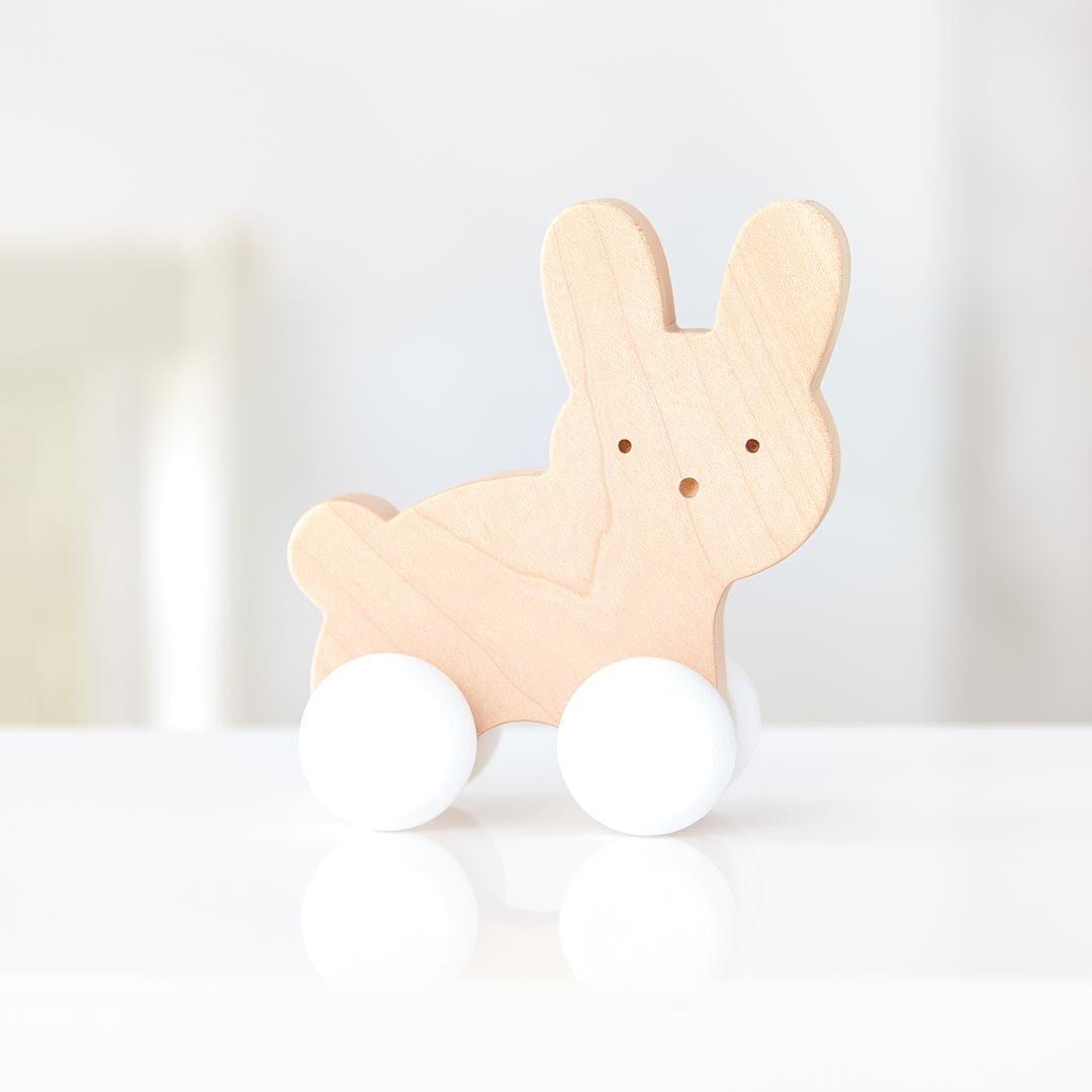 Jouet à pousser en forme de petit lapin en bois de hêtre, équipé de roues fluides pour encourager la motricité globale et accompagner les premiers déplacements de bébé.