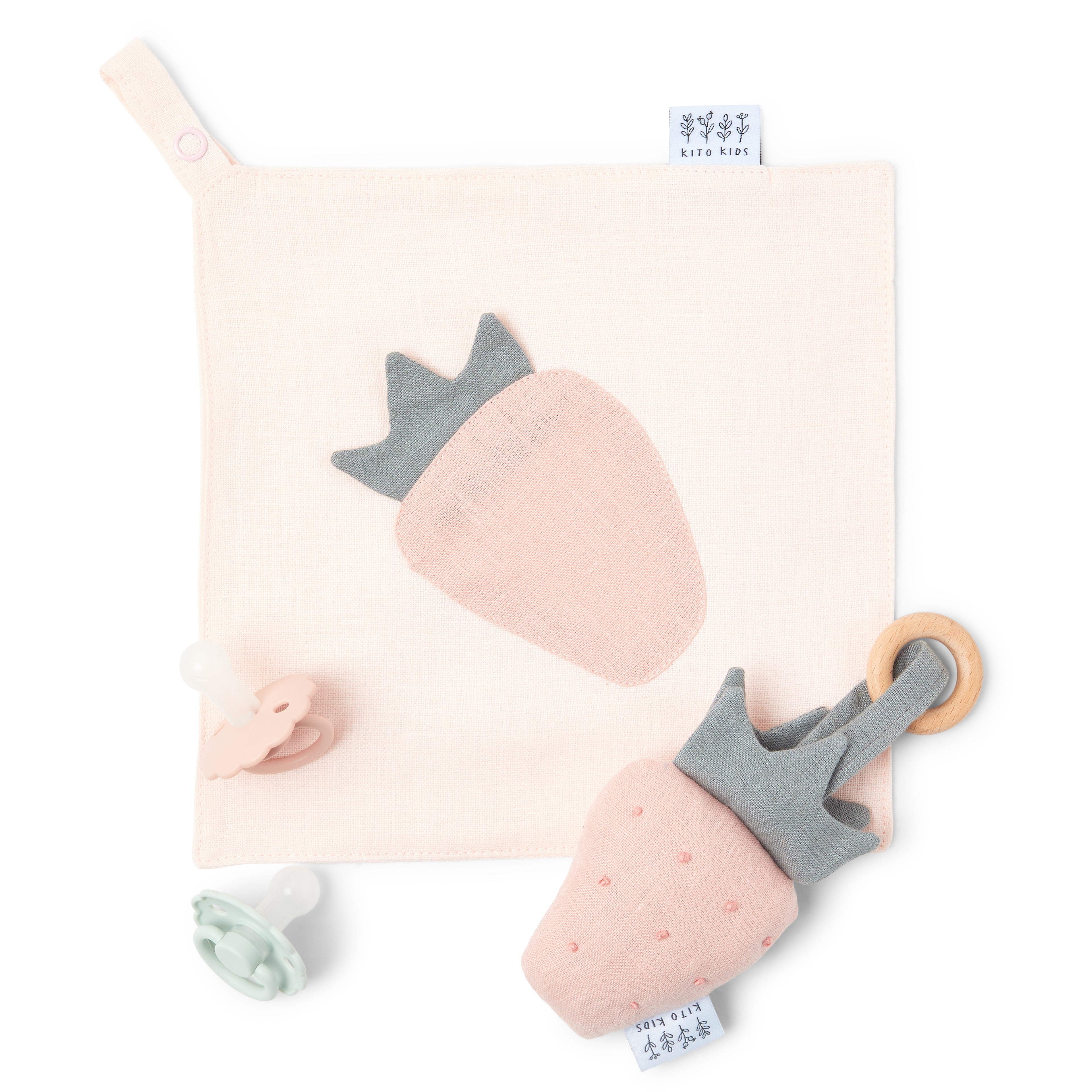 Kit d'éveil pour bébé Kito Kids comprenant un doudou plat fraise en coton bio, un hochet de dentition en bois assorti et deux tétines.
