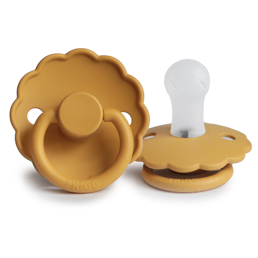 Sucette pour bébé Frigg en forme de marguerite couleur ocre avec sa collerette festonnée et sa tétine en silicone semi-transparent.
