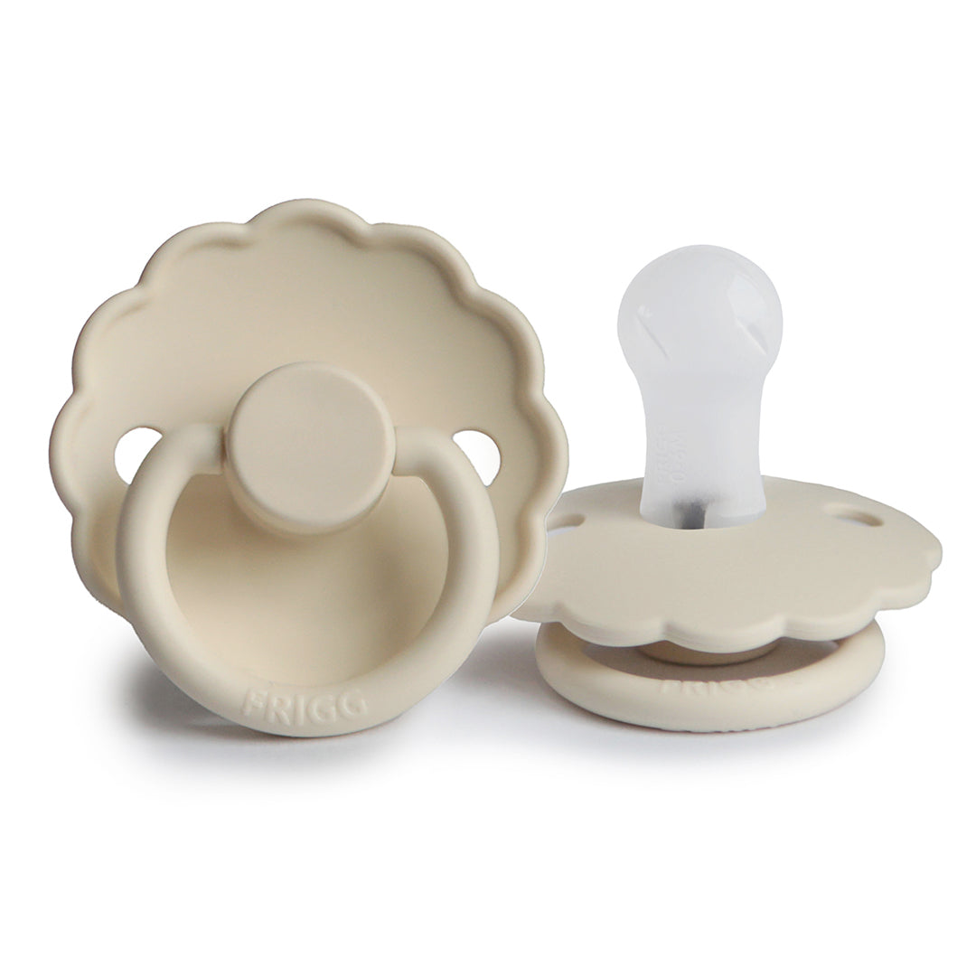 Sucette en silicone couleur crème ou sable beige, présentant le modèle de face avec ses bordures festonnées et le modèle de profil dévoilant l'embout de succion translucide.