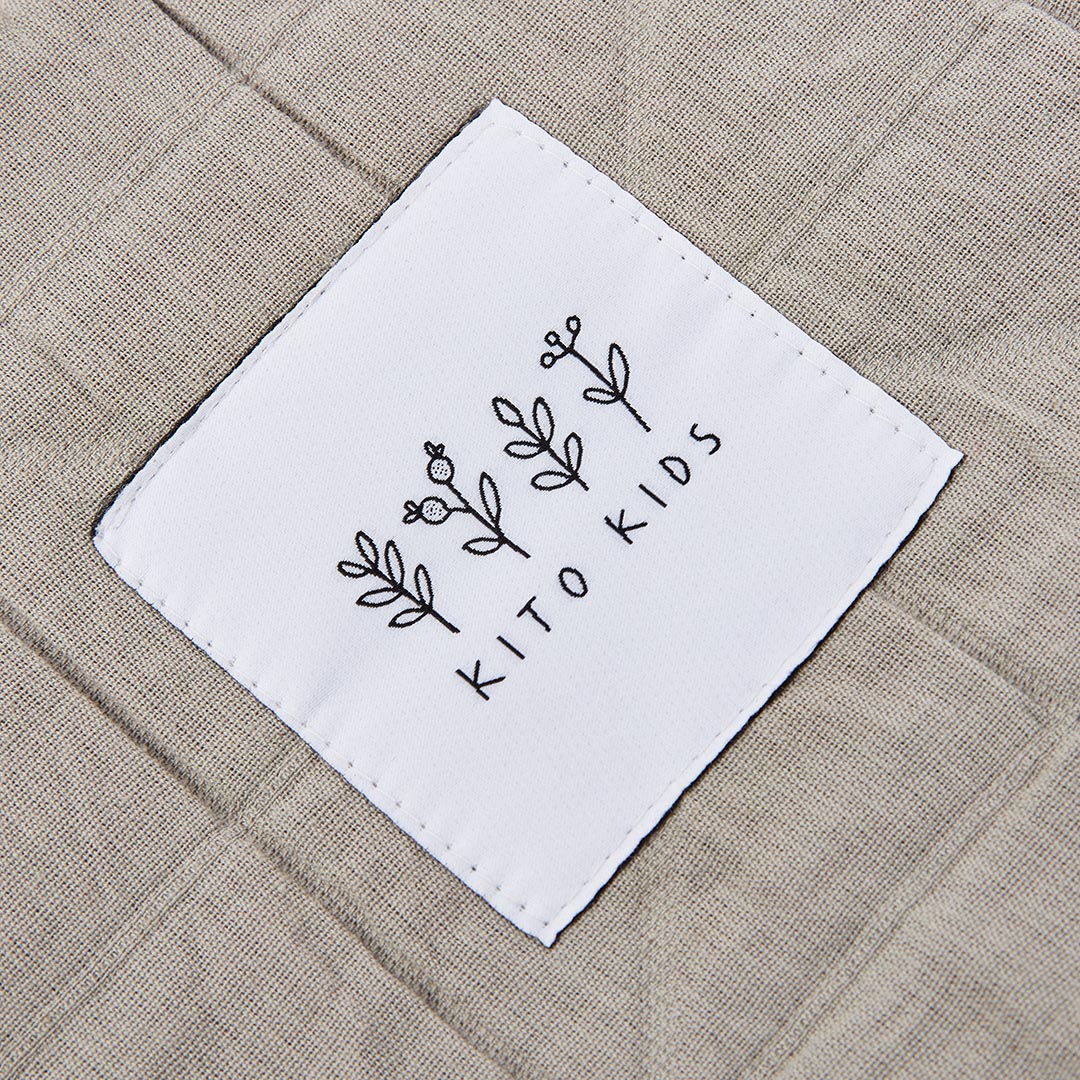 Trousses de toilette Kito Kids de couleur vert kaki et crème, présentées avec des produits cosmétiques et de toilette pour bébé.